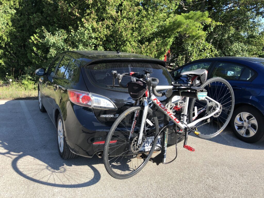 Voiture noire avec un vélo attaché à l'arrière dans l'article qui s'intitule ''Visiter l'Ontario à vélo'' 
