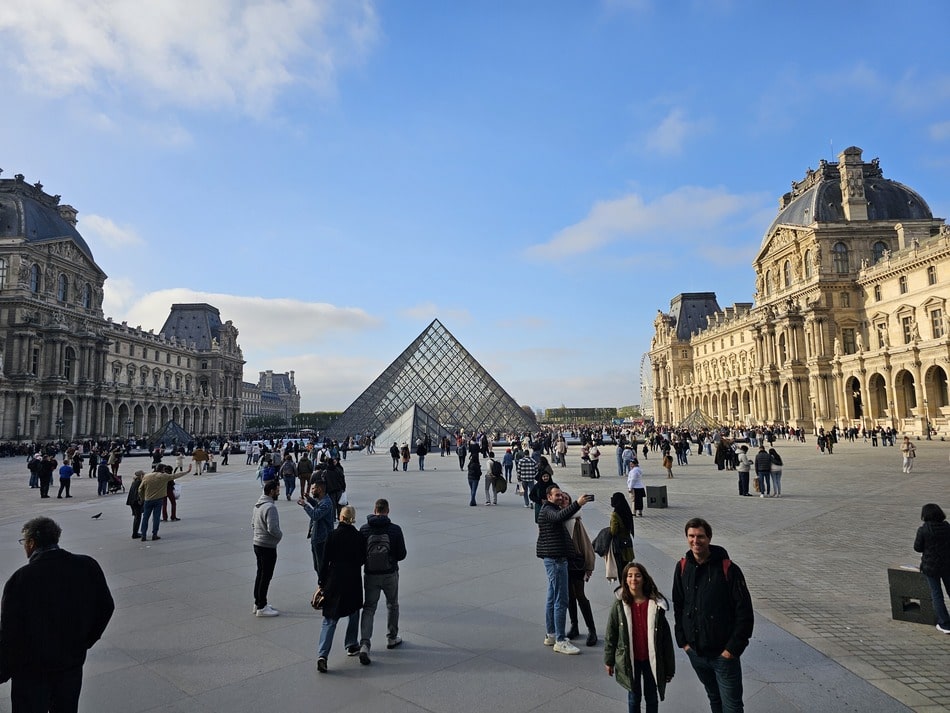 Musée du Louvre avec ses pyramides et des visiteurs autour