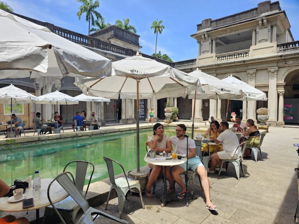 Couples qui mangent sous des parasols près d'une piscine