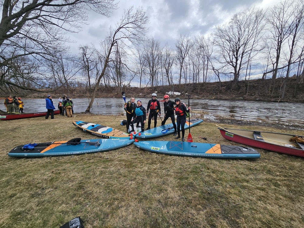 5 personnes avec leurs paddleboard face à la rivière Moi et ma médaille à la fin de la course sur la Raisin River 2025 dans mon article Récit d’un choc post-traumatique sur la rivière Missisquoi en paddleboard #paddleboard #chocposttraumatique #reflexion #SUP