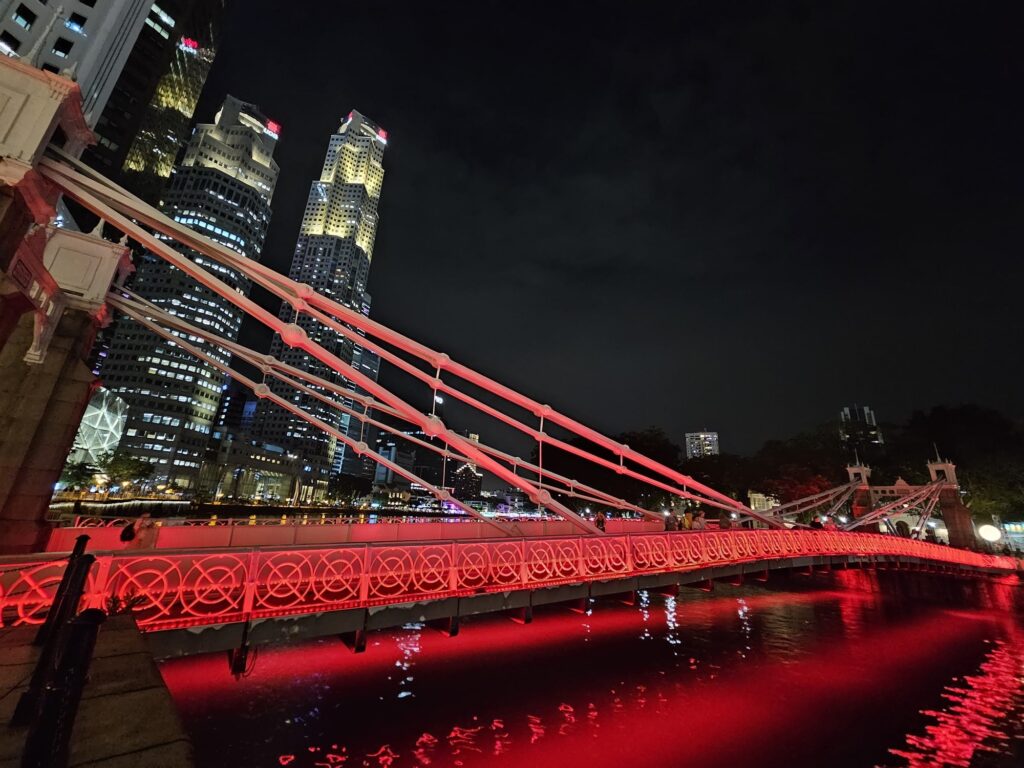 Pont rouge tout illuminé servant à traverser la rivière Singapour d'une rive à l'autre, au beau milieu du centre-ville