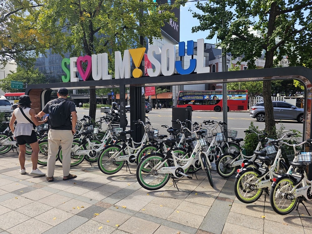 Stationnement à vélos à Séoul avec un tag coloré au-dessus portant l’inscription "Seoul my Soul".