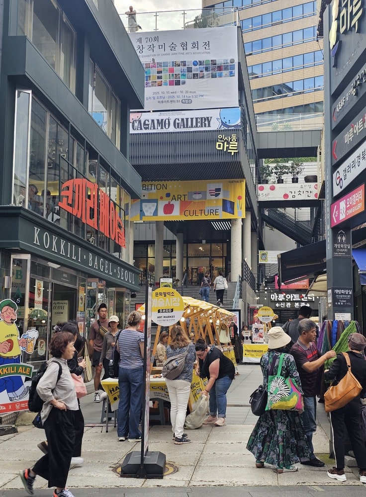 Rue animée de la rue Isandong à Séoul avec des passants, des stands de marché et des boutiques modernes, sous un ciel dégagé
