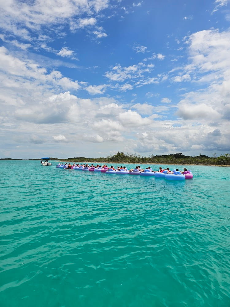 Un bateau qui tire des dizaines de personnes sur des tubes dans l'eau turquoise